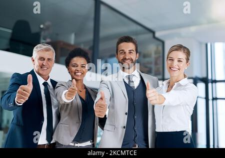 Happy colleagues means a happy business. a motivated business team showing thumbs up and smiling. Stock Photo