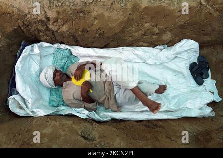 A farmer lies inside a grave as they stage 'Zameen Samadhi' protest over three farm laws and an increase in land compensation, at Ghaziabad's Mandola village in the northern state of Uttar Pradesh, India on September 21, 2021. (Photo by Mayank Makhija/NurPhoto) Stock Photo