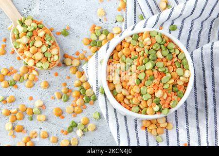 Different types of peas yellow and green in white bowl on grey stone background Stock Photo