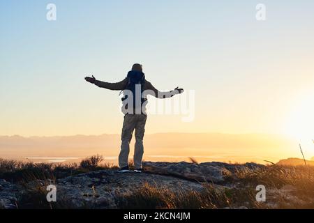 The world is your oyster. a hiker with his arms raised standing on top of a mountain. Stock Photo