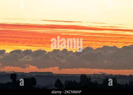 Dawn sky over Thanet and the Kent landscape seen from Herne Bay. Winter, with layers of cloud in the sky, underlit by the still to rise sun making them orange and yellow. Stock Photo