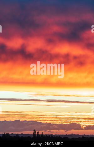 Dawn sky over Thanet and the Kent landscape seen from Herne Bay. Winter, with layers of cloud in the sky, underlit by the still to rise sun making them orange and yellow. Stock Photo