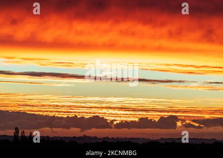 Dawn sky over Thanet and the Kent landscape seen from Herne Bay. Winter, with layers of cloud in the sky, underlit by the still to rise sun making them orange and yellow. Stock Photo