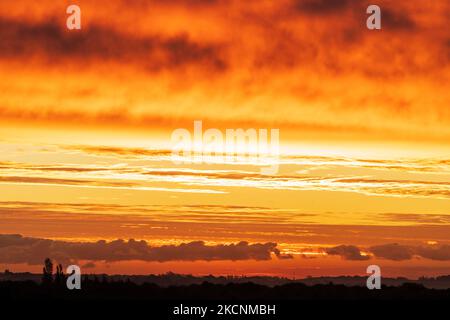 Dawn sky over Thanet and the Kent landscape seen from Herne Bay. Winter, with layers of cloud in the sky, underlit by the still to rise sun making them orange and yellow. Stock Photo