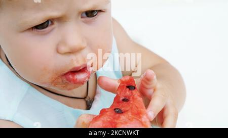 summer, in the garden, funny one-year-old blond girl eating watermelon. High quality photo Stock Photo