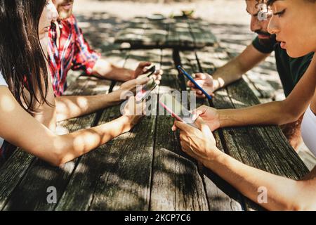 Group of young person using smartphone sitting outdoors - people phubbing using social network - gen z people addicted by the internet and cellphones Stock Photo