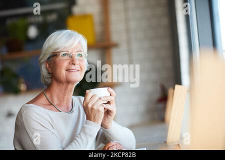 Some coffee to accompany her contemplation. a senior man looking thoughtful while sitting in his local coffee shop. Stock Photo