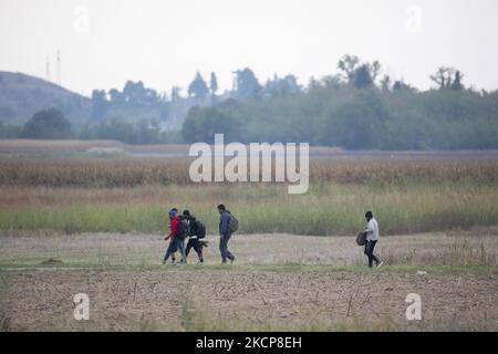 Asylum Seekers are trying to cross the Greek-North Macedonian borders to follow the Balkan Route, famous in 2015-2016 during the Syrian refugee crisis, from Idomeni, Greece to Gevgelija, North Macedonia following the train rails and railway station and then reach central and northern Europe. Refugees and Migrants are seen walking in the fields in the Greek side, before the fence that separates the two countries, trying to reach and pass the borders. The small groups are mostly male dominated from Afghanistan, newcomers who began their trip after the Taliban takeover of the country. Among them  Stock Photo