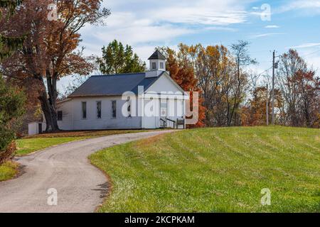 An old white wooden clapboard country church, typical of those found in rural Appalachia on winding road in autumn.