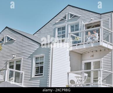 Couple, love and breakfast on the balcony while on vacation together for bonding. House, holiday and young man and woman drinking tea or coffee with a Stock Photo