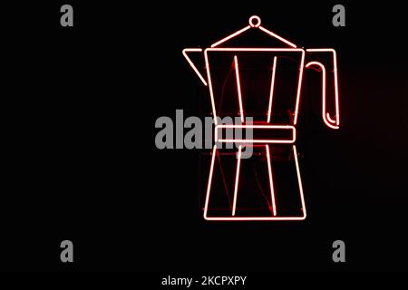 Red neon sign from lamps in the form of a Moka pot coffee maker on the wall of a black coffee shop. Stock Photo