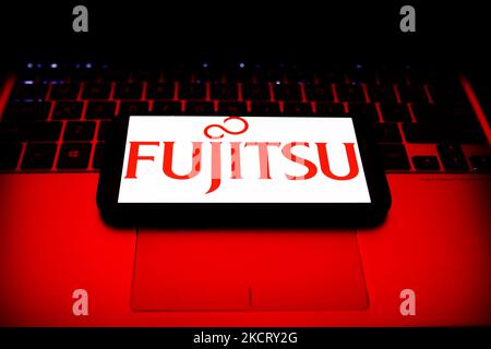 Fujitsu logo displayed on a phone screen and a laptop keyboard are seen in this illustration photo taken in Krakow, Poland on October 30, 2021. (Photo by Jakub Porzycki/NurPhoto) Stock Photo