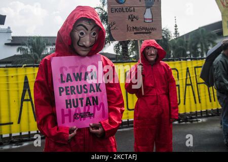 A man dressed as in the movie series 'Money Heist' holds a placard containing a protest about the climate crisis during action on November 5, 2021 in Bandung, West Java, Indonesia. Bandung BERISIK (United to Save the Climate) urges the Indonesian government to review and even stop all forms of development activities that damage the environment and contribute significantly to overcoming the climate crisis. (Photo by Algi Febri Sugita/NurPhoto) Stock Photo