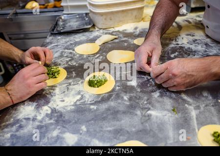 Detail of the frittelle being prepared by Salvatore Verdesca and his collaborators in his bakery on the occasion of San Martino on 11 November 2021 in Molfetta. In San Martino a Molfetta it is traditional to prepare frittelle, a kind of stuffed panzerotto. Already in the early morning the alleys, streets, apartment buildings, every corner of the city, in short, is invaded by that smell of genuine fried food. The mass, already processed and leavened, is ready early in the morning for the fillings of the famous and tasty frittelle by Molfetta from the more traditional ones with mozzarella, onion Stock Photo