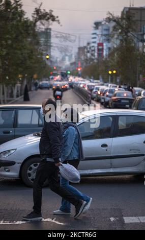 An Iranian man and a woman wearing protective face masks cross an avenue while shopping in downtown Tehran, amid the COVID-19 outbreak in Iran, November 12, 2021. (Photo by Morteza Nikoubazl/NurPhoto) Stock Photo