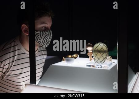 LONDON, UNITED KINGDOM - NOVEMBER 17, 2021: A staff member looks at the Diamond Trellis Egg (R), the Third Imperial Easter Egg (C) and the Hen Egg (L) during a photocall for the upcoming exhibition 'Faberge in London: Romance to Revolution' at the V&A (20 November 2021 – 8 May 2022), on 17 November, 2021 in London, England. The V&A’s major exhibition with over 200 objects on display including a collection of Imperial Easter Eggs will explore craftsmanship of master Russian goldsmith Carl Faberge and the Anglo-Russian nature of his enterprise. (Photo by WIktor Szymanowicz/NurPhoto) Stock Photo