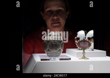 LONDON, UNITED KINGDOM - NOVEMBER 17, 2021: A staff member looks at the Red Cross with Triptych Egg (R) and the Mosaic Egg (L) during a photocall for the upcoming exhibition 'Faberge in London: Romance to Revolution' at the V&A (20 November 2021 – 8 May 2022), on 17 November, 2021 in London, England. The V&A’s major exhibition with over 200 objects on display including a collection of Imperial Easter Eggs will explore craftsmanship of master Russian goldsmith Carl Faberge and the Anglo-Russian nature of his enterprise. (Photo by WIktor Szymanowicz/NurPhoto) Stock Photo