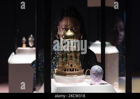 LONDON, UNITED KINGDOM - NOVEMBER 17, 2021: A staff member looks at the Moscow Kremlin Egg – the largest Imperial Egg – inspired by the architecture of the Dormition Cathedral, on loan from the Moscow Kremlin Museums (L) and the Swann Egg (R) during a photocall for the upcoming exhibition 'Faberge in London: Romance to Revolution' at the V&A (20 November 2021 – 8 May 2022), on 17 November, 2021 in London, England. The V&A’s major exhibition with over 200 objects on display including a collection of Imperial Easter Eggs will explore craftsmanship of master Russian goldsmith Carl Faberge and the Stock Photo