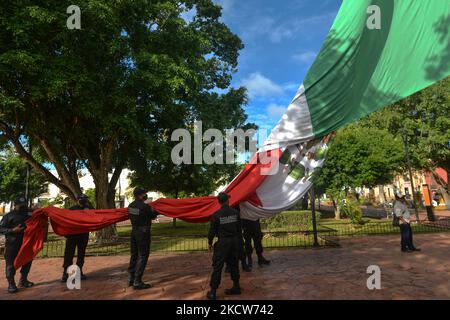 Members of the municipal police (Policía Municipal de Valladolid) fold the national flag of Mexico after the short ceremony of El Día de la Revolucion (Revolution Day), a national holiday commemorating the beginning of the Mexican Revolution on November 20, 1910. Official Revolution Day celebrations have been canceled due to the Covid-19 pandemic. The city of Valladolid was the site of the 'first spark of the Mexican Revolution,' also known as the Dzelkoop Plan, an uprising that began on June 4, 1910, by Maximiliano R. Bonilla and other leaders of the Independent Electoral Center and the Anti  Stock Photo