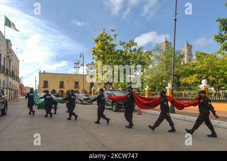 Members of the municipal police (Policía Municipal de Valladolid) carry the national flag of Mexico to the Town Hall after the short ceremony of El Día de la Revolucion (Revolution Day), a national holiday commemorating the beginning of the Mexican Revolution on November 20, 1910. Official Revolution Day celebrations have been canceled due to the Covid-19 pandemic. The city of Valladolid was the site of the 'first spark of the Mexican Revolution,' also known as the Dzelkoop Plan, an uprising that began on June 4, 1910, by Maximiliano R. Bonilla and other leaders of the Independent Electoral Ce Stock Photo