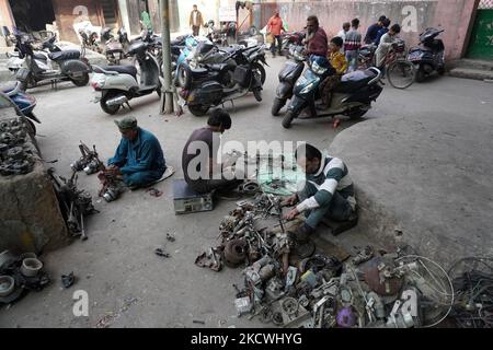 Workers flatten metal scrap from automobile parts outside a workshop in New Delhi, India on November 24, 2021. The Reserve Bank of India forecasts 9.5 per cent GDP growth this fiscal year, while the average projection ranges between 8.5 per cent and 10 per cent, from the earlier estimate of 8 per cent for calendar year 2022. (Photo by Mayank Makhija/NurPhoto) Stock Photo