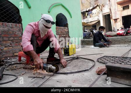 A worker cuts iron rods to make a frame outside a workshop in New Delhi, India on November 25, 2021. The Reserve Bank of India forecasts 9.5 per cent GDP growth this fiscal year, while the average projection ranges between 8.5 per cent and 10 per cent, from the earlier estimate of 8 per cent for calendar year 2022. (Photo by Mayank Makhija/NurPhoto) Stock Photo