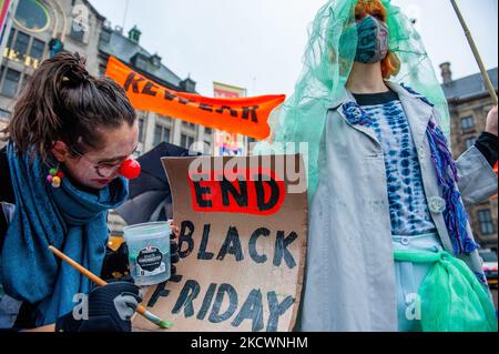 A clown representing the greenwashing practices carried out by fashion brands, is pretending painting with green paint, during a mocking Fast fashion parade organized by XR, against Black Friday in Amsterdam, on November 27th, 2021. (Photo by Romy Arroyo Fernandez/NurPhoto) Stock Photo