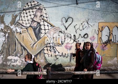 Palestinian children walk past a mural in Gaza City, on November 28, 2021. (Photo by Majdi Fathi/NurPhoto) Stock Photo