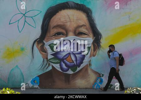 A man walks past a mural portraying a Mayan woman wearing a face mask, painted in the center of Merida by Mexican artist Arnold Cruz, better known as 'Datoer'. The artwork is related to Covid-19 pandemics and painted to give recognition and appreciation to these 'heroes' who risk their lives to fight the virus. On Sunday, November 28, 2021, in Merida, Yucatan, Mexico. (Photo by Artur Widak/NurPhoto) Stock Photo