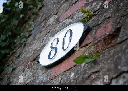 Identification plate on an old bridge over a canal showing the number 80 printed black on a white background