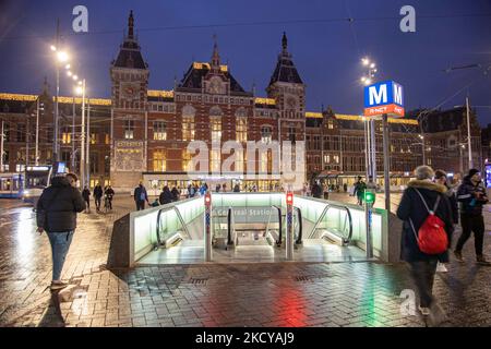 People outside of Amsterdam Centraal with the escalator leading to the Metro stop underground, the main railway station of the city. Streets of Amsterdam during the first day of the sudden lockdown in Dutch capital city. The first European nation declares a full lockdown to fight the new Omicron variant that surges, the Netherlands locks down after the government ordered the closure of all nonessential shops, cafes, restaurants, bars, gyms, schools, sports venues, cultural places and others from Sunday and for 4 weeks in order to prevent the spread of the Omicron mutation of Covid-19 coronavir Stock Photo