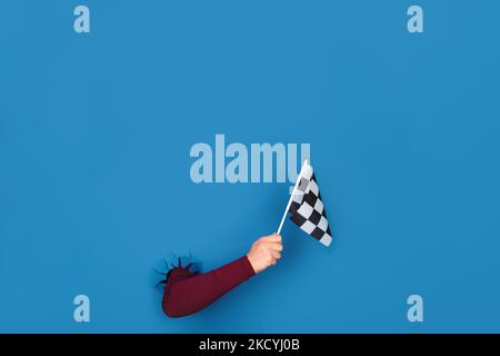 hand holding checkered flag over blue background Stock Photo