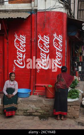 Newari women in traditional attire sit in front of a shop with Coke advertisements as they sell fresh vegetables by the roadside in the ancient city of Bhaktapur in Nepal. (Photo by Creative Touch Imaging Ltd./NurPhoto) Stock Photo