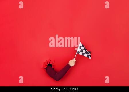 checkered flag in hand over red background, layout image Stock Photo