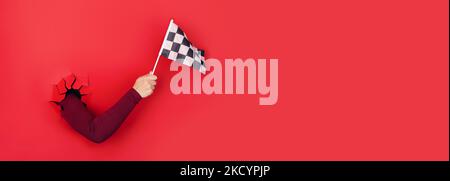 checkered flag in hand over red background, panoramic layout Stock Photo