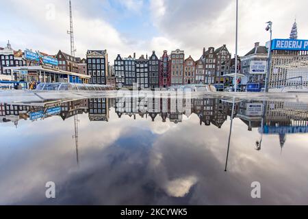 Reflection of the reclining houses. The empty canals of Amsterdam with the tourist sightseeing boats docked. Quiet, almost deserted from local people and tourists streets of Amsterdam during the lockdown in the Dutch capital city with stores and shops appearing with closed with the roller metal shutter down, cafes, bars and restaurants also closed with tables and chairs of the terraces locked. The Netherlands was the first European nation to declare full lockdown to fight the new Omicron variant that surges. After a sudden government order before Christmas, the country closed all the nonessent Stock Photo