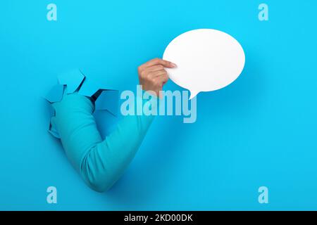 Talk bubble speech icon in hand over blue background Stock Photo
