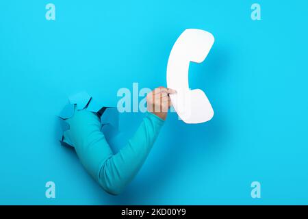 handset in hand over blue background Stock Photo