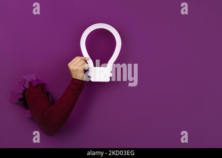 hand holding light bulb over purple background, new idea concept Stock Photo