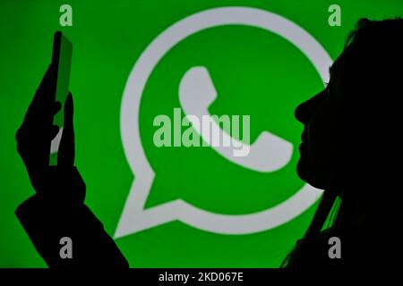 An image of a woman holding a cell phone in front of a WhatsApp Messenger logo displayed on a computer screen. On Tuesday, January 12, 2021, in Edmonton, Alberta, Canada. (Photo by Artur Widak/NurPhoto) Stock Photo