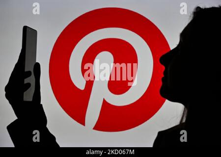 An image of a woman holding a cell phone in front of a Pinterest logo displayed on a computer screen. On Tuesday, January 12, 2021, in Edmonton, Alberta, Canada. (Photo by Artur Widak/NurPhoto) Stock Photo