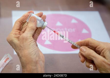Close-up at the syringe, vial and hands of a woman preparing the booster shot. GGD public medical healthcare worker prepares the Moderna Spikevax mRNA Covid-19 vaccines drawing them from the vial glass bottle to individual doses in the syringes at the special area in the mega vaccination center in Eindhoven. The jabs are administered as a booster shot. The third-dose booster is available for all in the Netherlands in addition to the lockdown as the nation battles outbreaks of the new omicron variant coronavirus mutation of the pandemic. Eindhoven, The Netherlands on January 7, 2022 (Photo by N Stock Photo
