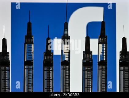 Illustrative photo of medical syringes seen in front of a Facebook logo displayed on a computer screen. On Thursday, January 14, 2021, in Edmonton, Alberta, Canada. (Photo by Artur Widak/NurPhoto) Stock Photo