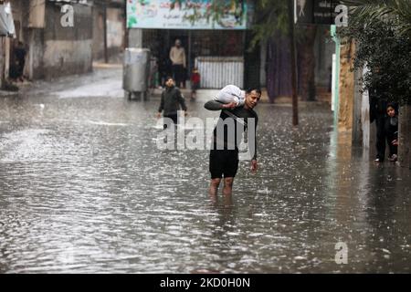 Palestinians walk on a flooded street following heavy rain in the northern Gaza Strip, on January 16, 2022. (Photo by Majdi Fathi/NurPhoto) Stock Photo