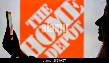 An image of a woman holding a cell phone in front of The Home Depot logo displayed on a computer screen. On Tuesday, January 12, 2021, in Edmonton, Alberta, Canada. (Photo by Artur Widak/NurPhoto) Stock Photo