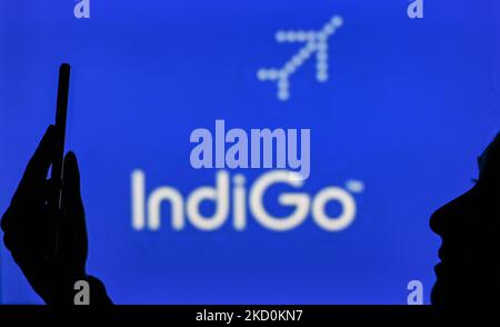 An image of a woman holding a cell phone in front of the IndiGo Airline logo displayed on a computer screen. On Tuesday, January 12, 2021, in Edmonton, Alberta, Canada. (Photo by Artur Widak/NurPhoto) Stock Photo