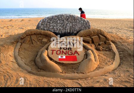 A sand sculpture of the massive volcanic eruption and tsunami alert in Tonga is creating by the Indian sand artist Sudarsan Pattnaik with the message ''Pray for Tonga'' at the Bay of Bengal Sea's eastern coast beach Puri , 65 km away from the eastern Indian state Odisha's capital city Bhubaneswar, on 20 January 2022. (Photo by STR/NurPhoto) Stock Photo