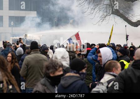 Demonstrators are sprayed from water cannons while clashing with police. Thousands Protest during the European Demonstration for Democracy against Covid-related measures like the COVID Health Pass And Restrictions. Riots started breaking out and police fire tear gas and water cannon as the protest turned violent. People take part in a demonstration against health measures in Brussels like the COVID Health Pass, the QR code, facemasks and the mandatory vaccination, using as a main slogan and on banners the word liberte translated as freedom. Authorities estimated that around 50,000 people from  Stock Photo