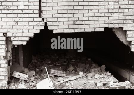Building exterior brick wall with extreme damage cracks holding up from vehicle collision.Sepia black and white photo abstract background photo. Stock Photo