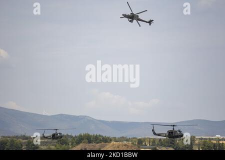 A Boeing AH-64 Apache helicopter from the Greek Army as seen flying and manoeuvering with two Bell UH-1 Iroquois Huey helicopters below during a flying display demonstration during Athens Flying Week 2021 Air Show at Tanagra Air Base Airport. The Apache of the Hellenic military is the AH-64D Apache Longbow version. The specific aircraft is a twin turboshaft attack combat helicopter under the fuselage and on the wings with a machine gun, missiles, rocket and self defense capabilities. Greece, a country with strong air force is a member state of the North Atlantic Treaty Organization NATO. Tanag Stock Photo